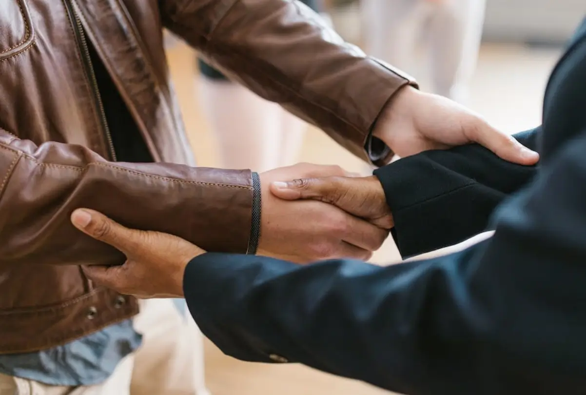 Two people holding hands while wearing leather jackets.